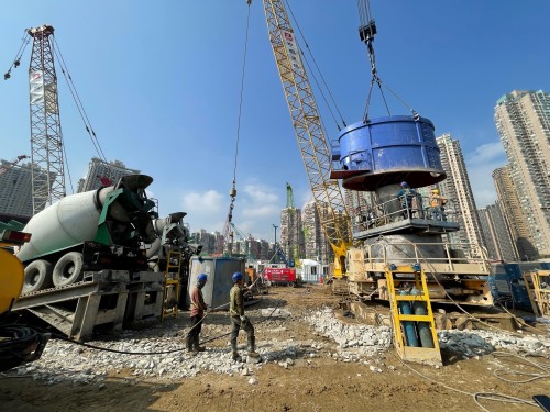 Workers pour concrete into bored pile.